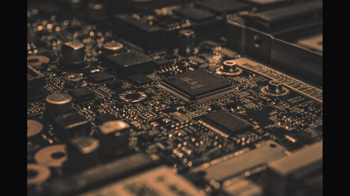Macro photograph of a dense circuit board showing a central processor package and surrounding components.