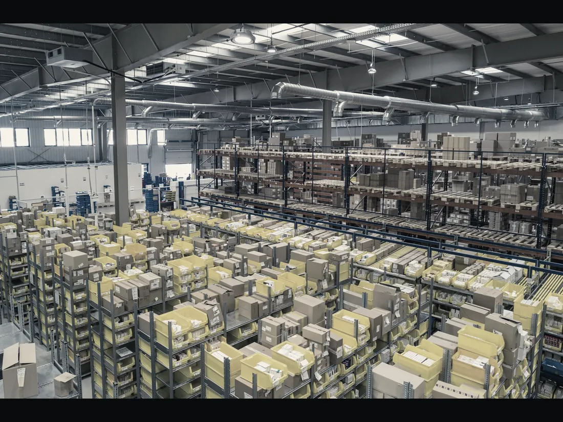 Wide view of a distribution warehouse with racked yellow totes stretching into the distance.