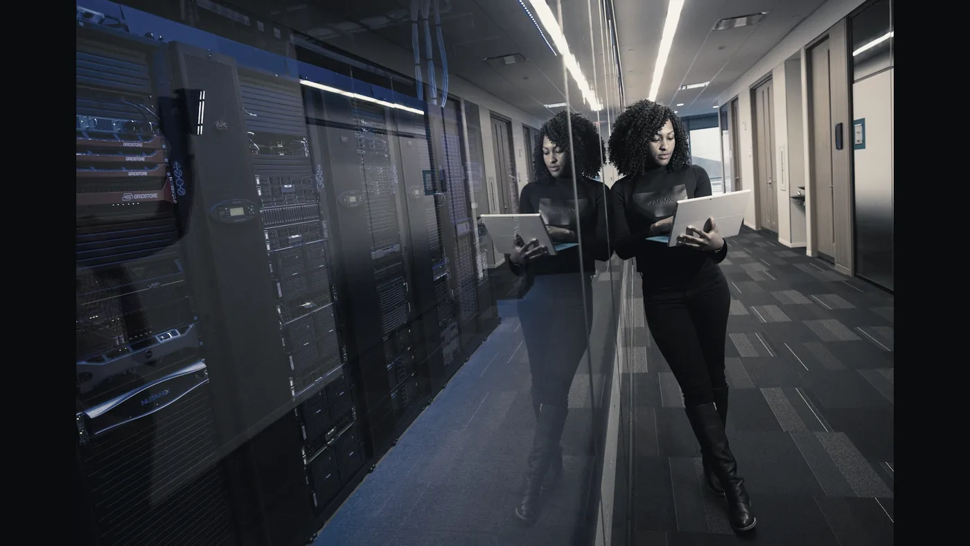 Operations corridor lined with illuminated equipment racks, a supervisor walking between them.