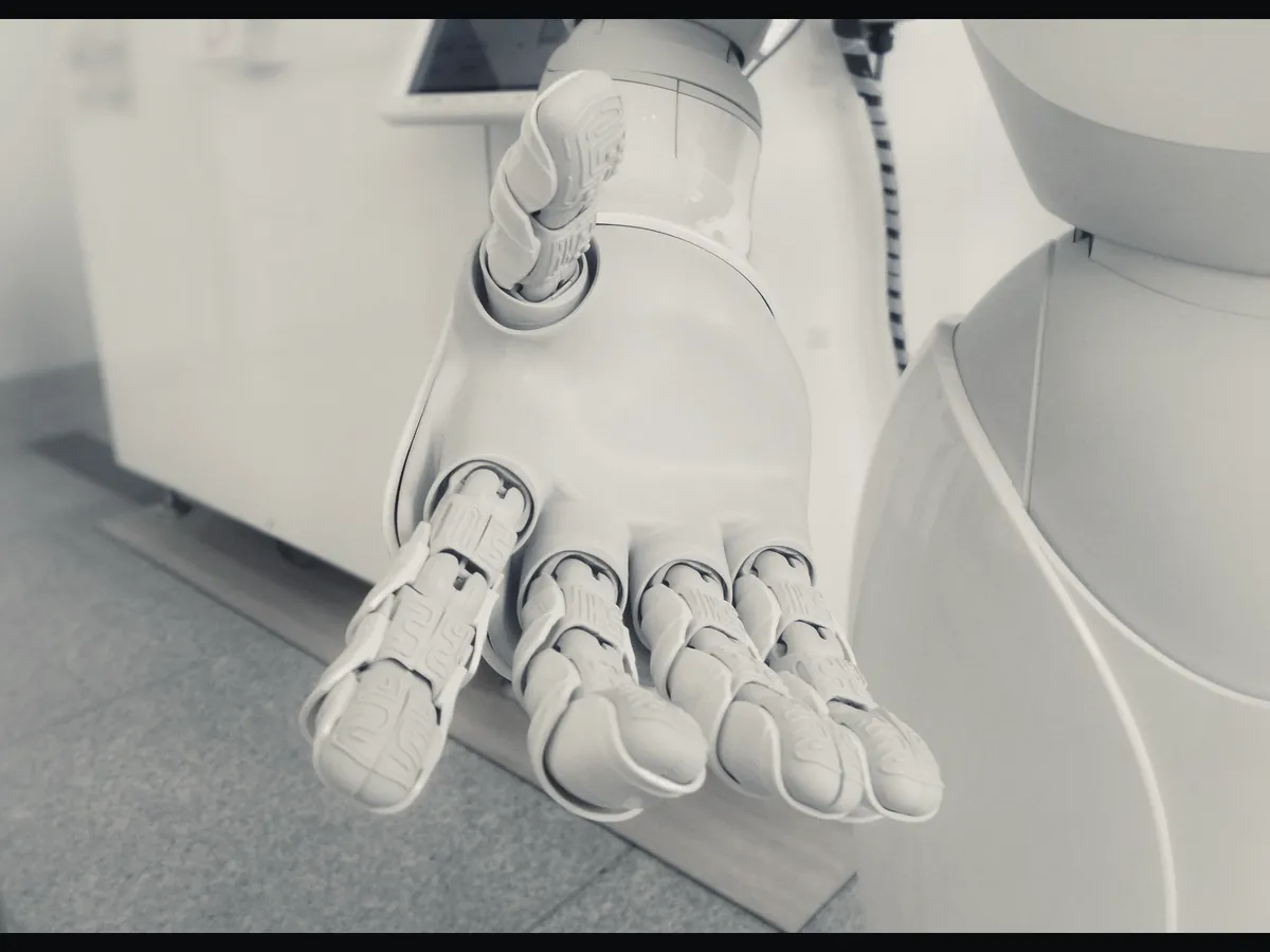 Close-up of a white five-digit robotic hand with articulated finger joints.